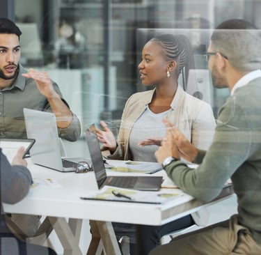 Team in a meeting discussing work around a table at a tech company