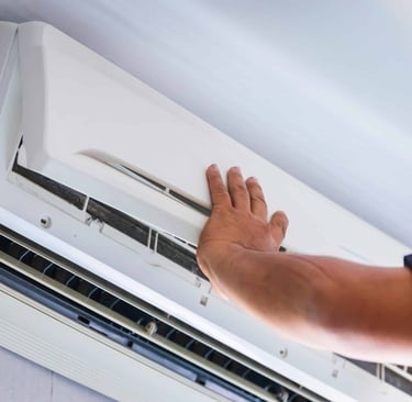 a person holding a hand over a white air conditioner