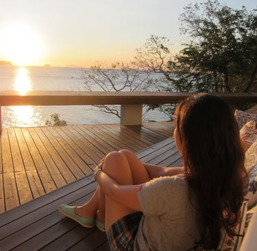a woman sitting on a couch with a view of the ocean