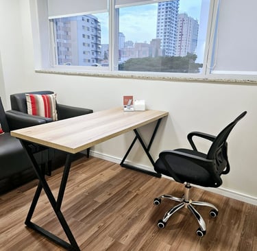 Consultório de psicologia ou psiquiatria vazio, com duas poltronas, uma mesa e uma cadeira de escrit