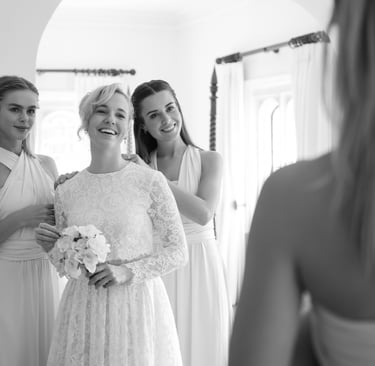 black & white reflection photo of bride and bridesmaids, looking in the mirror laughing and having a good time