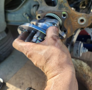Fast T's Technicians hand lifting a wheel bearing assembly into place for installation 