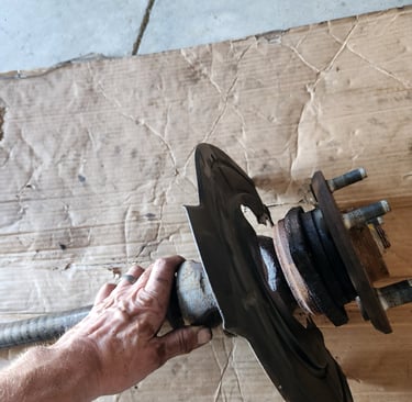 Fast T's Master Mechanic removing an axle from a 2014 Jeep Wrangler Unlimited Sport and placing it on a piece of cardboard on