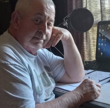 a man sitting at a desk with a laptop and a microphone