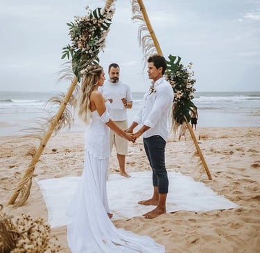 a bride and groom standing on the beach