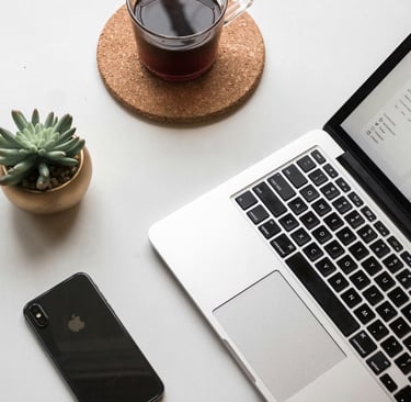 MacBook computer with cup of coffee and a cactus on an office desk