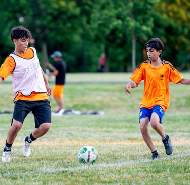 Two MVB F.C. soccer players playing soccer on a grassy field Mississauga
