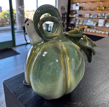 A small ceramic pumpkin with a twirled handle and a little ghost. 