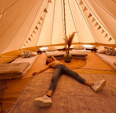a woman laying on a rug in a glamping tent, la sensacion