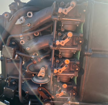 Close-up of a multi-carburetor boat engine assembly showing complex mechanical linkages and intake manifolds.