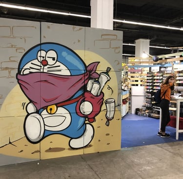 Un dibujo de doraemon en el salón del manga hecho en unos cartones. Pintura en directo.