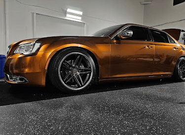Metallic bronze vinyl wrap on a Chrysler 300 sedan with dark wheels, expertly installed in the shop.