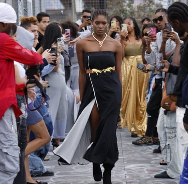 a woman in a black dress walking down a street