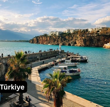 A bright, panoramic view of the Old Harbor (Kaleiçi Marina) in Antalya, Türkiye. The turquoise Medit