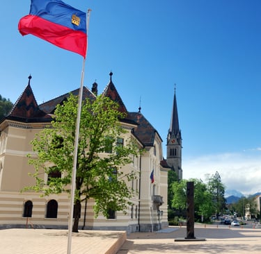 Vibrant spring scene of Vaduz, Liechtenstein, featuring the national flag waving in front of the his