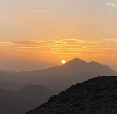 a person standing on a mountain top with a sunset