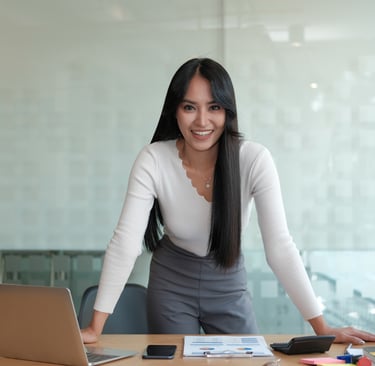 Curso de Assistente Contábil: Imagem de uma mulher sorrindo apoiada em uma mesa de escritório