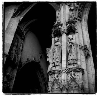 A picture of an architecture in Paris, an entrance to the old church. A column with two sculptures. Creator: Slawek Dejneka