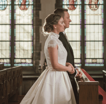 a bride and groom standing in front of a church