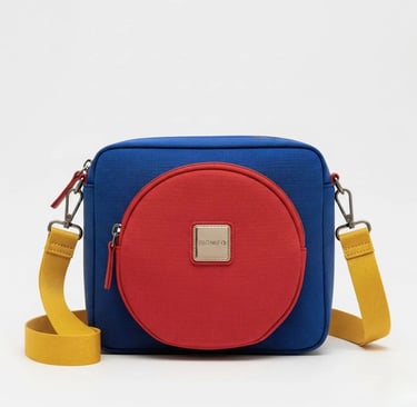 Tas selempang SIGNIFO berwarna biru dengan kantong lingkaran berwarna merah di tengahnya.