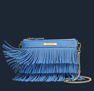 Tas selempang rumbai berwarna biru pastel dengan tali rantai emas di latar belakang putih.