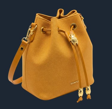 Tas serut bucket berwarna kuning busuk dengan detail kumbang scarab emas di latar belakang putih.
