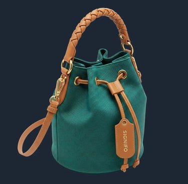 Tas bucket dari kain kanvas hijau sage SIGNIFO dengan handle kulit anyam dan tali selempang.