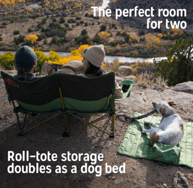 Camping couple sitting in a Kelty loveseat camping chair, with dog using roll-tote bag as bed