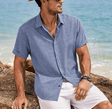 a man in a hat and sunglasses sitting on a rock