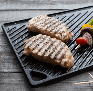 a grilling pan with meat and vegetables on it