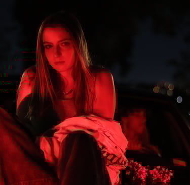 Photo of Audra Baruch on top of a car underneath a red light