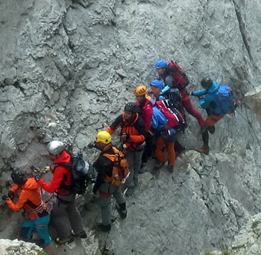 Group of climbers attached to a cable on a mountain side.