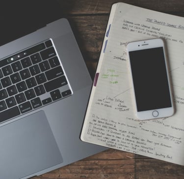 a laptop computer and a notebook with a planner and a cell phone virtual assistant