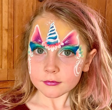 a young girl with a floral unicorn face paint on her face