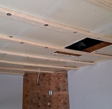 Ceiling strapping and drywall installation above fireplace during residential interior renovation