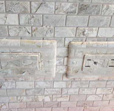 Switch plate faux finished to match the marbled tiles of this backsplash to hide them nicely.