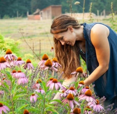 a woman in a blue shirt is looking at a flower