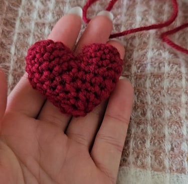 a red amigurumi heart in someones hand