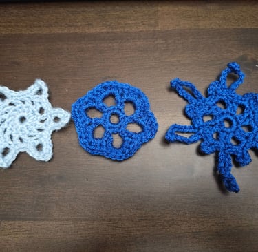 three crochet snowflakes on a wooden table