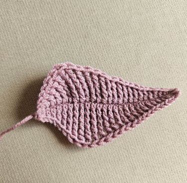 Handmade dusty rose crochet leaf applique featuring detailed texture on a neutral background.