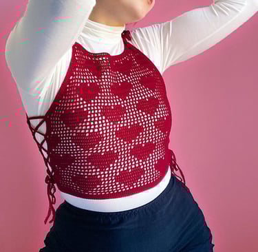 a woman with a red heart design crochet shirt on top of a white shirt