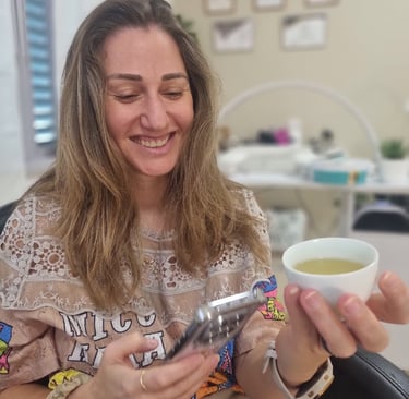 אישה יושבת בחדר טיפולים ונהנית מכוס תה חם תוך כדי מנוחה.