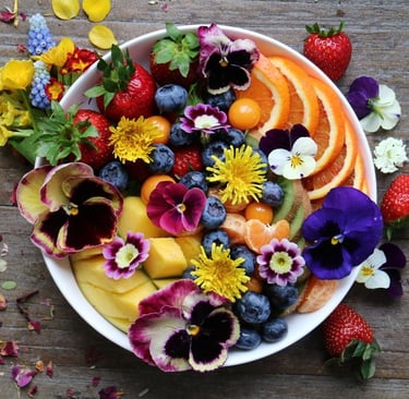 a bowl of fruit and flowers on a table