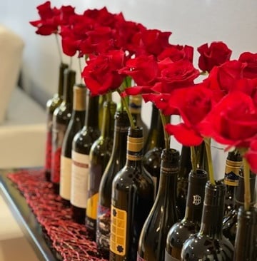 a row of wine bottles with red roses in them