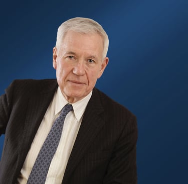 Alain Brun in a suit and tie with a blue background