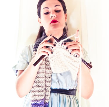 A woman knitting a long scarf.