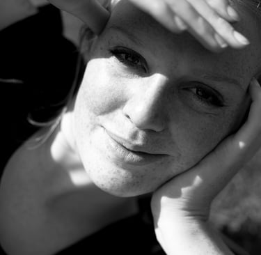 A woman lying down protecting her eyes from the sun.