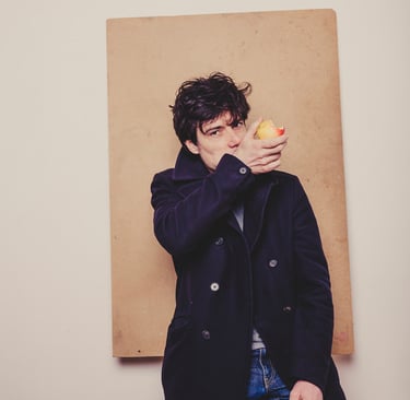 A man eating an apple in a navy coat.