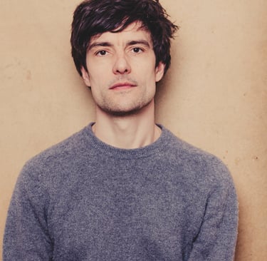 Portrait of musician Noel Rademacher in a grey sweater.