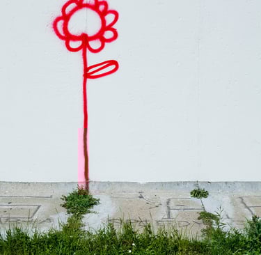 A red flower on a wall next to grass.